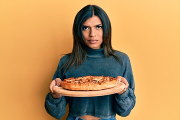Young latin transsexual transgender woman holding italian pizza skeptic and nervous, frowning upset because of problem. negative person.