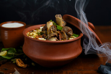 Gosht or Lamb Biryani prepared in Basmati Rice served with Yogurt dip in terracotta bowl. Selective focus