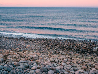 Natural background of pebbles on the seashore. The surface of the beach on the north ocean is covered with large polished round stones of gray color of different sizes