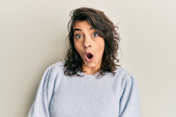 Young hispanic woman wearing casual winter sweater afraid and shocked with surprise expression, fear and excited face.