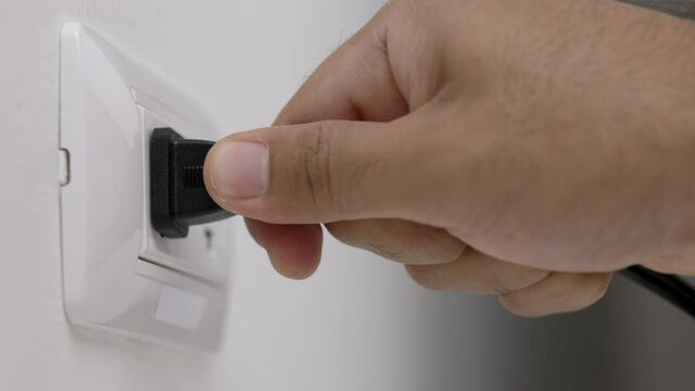 Hand remove Electric plug on socket. Electrical equipment, electrical wires and power strips in the house. Earth Hour saving electrical energy.