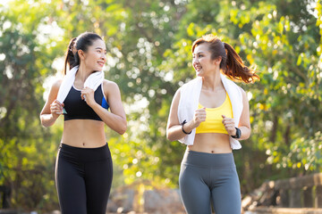 asian athletics couple woman jogging and exercising together in public park in the evening