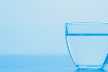 A cup of clear blue water. The concept of World Water Day.