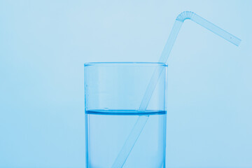 A glass of clear blue water with a drinking straw. The concept of World Water Day.