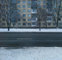 Naklejka premium View across an asphalt road to a house in a snowy city