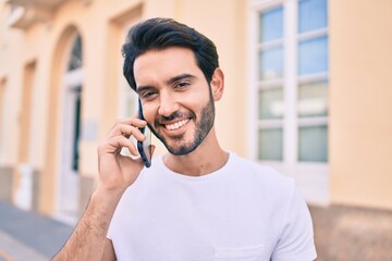 Young hispanic man smiling happy talking on the smartphone at city.