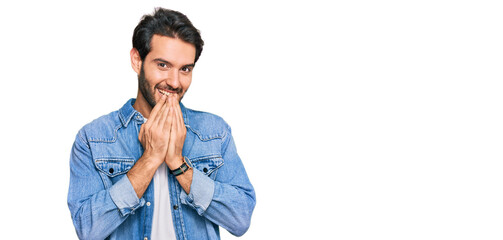 Young hispanic man wearing casual clothes laughing and embarrassed giggle covering mouth with...