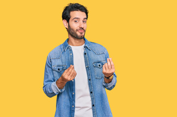 Young hispanic man wearing casual clothes doing money gesture with hands, asking for salary...