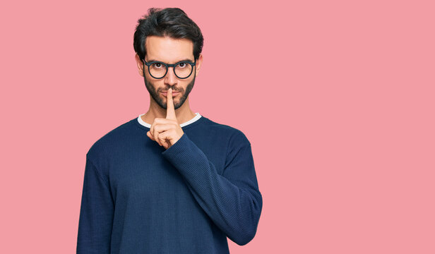 Young hispanic man wearing casual clothes and glasses asking to be quiet with finger on lips. silence and secret concept.