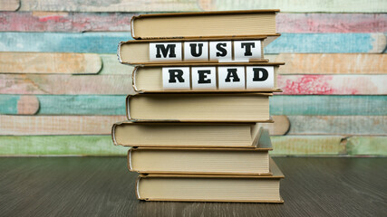 Phrase MUST READ appears on pile of books
