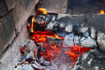 Glowing embers in hot red color, abstract background. The hot embers of burning wood log fire. Firewood burning on grill. Texture fire bonfire embers.