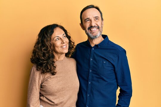 Middle Age Hispanic Couple Wearing Casual Clothes Smiling Looking To The Side And Staring Away Thinking.