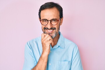 Middle age hispanic man wearing casual clothes and glasses smiling looking confident at the camera with crossed arms and hand on chin. thinking positive.
