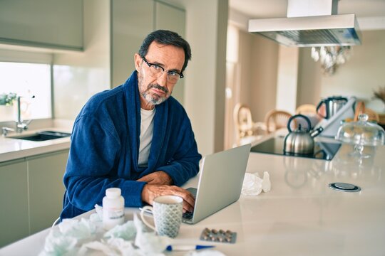 Middle age man feeling sick with cold and fever at home, ill with flu disease working from home