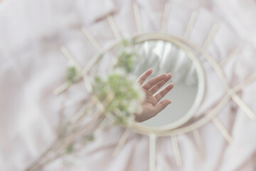 Hand reflected in mirror on background of soft fabric with manuka flowers, aesthetics. Mental Health