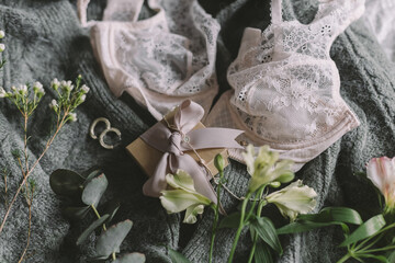 Stylish gift box, jewelry and spring flowers on sweater with lingerie. Soft image, woman essentials
