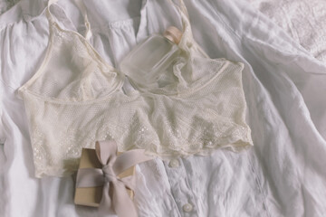 Stylish lace lingerie, gift box, perfume bottle on bed. Soft trendy image. Women's day