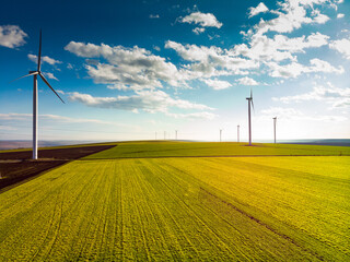 Obraz premium Beautiful bright Landscape with a Windfarm on a sunny day with a sky full of clouds and colorful foreground with green-yellowish grass