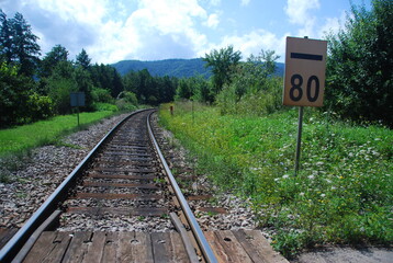 railway crossing in the countryside with a speed limit sign