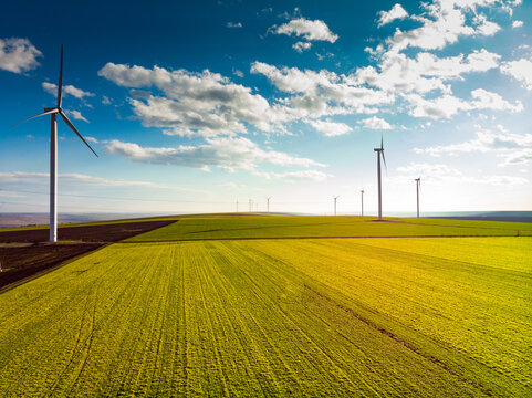 Beautiful bright Landscape with a Windfarm on a sunny day with a sky full of clouds and colorful foreground with green-yellowish grass