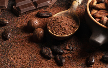 Chocolate and cocoa concept. Cocoa powder in a spoon near cocoa beans and broken chocolate on a...