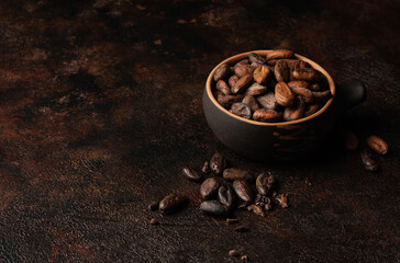 Chocolate and cocoa concept. Cocoa powder in bowl near cocoa beans on black background