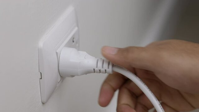 Hand holding Electric plug put on multiple socket. Electrical equipment, electrical wires and power strips in the house. Earth Hour saving electrical energy.
