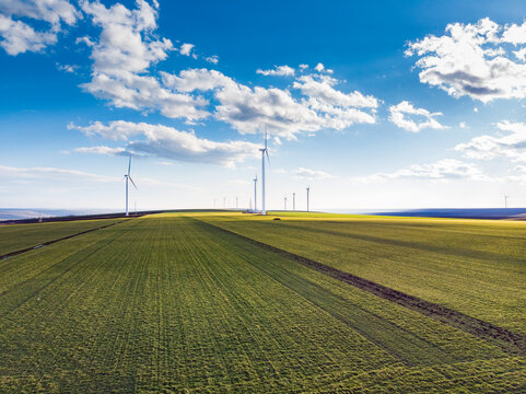 Beautiful bright Landscape with a Windfarm on a sunny day with a sky full of clouds and colorful foreground with green-yellowish grass