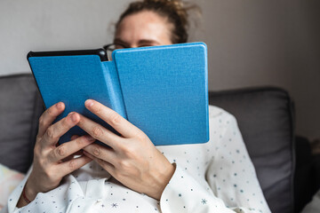 Relaxed woman reads with ebook at home.