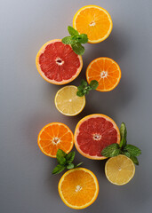 Cut in half fresh lemon, grapefruit, orange, tangerine with mint on a gray background, top view. Citrus juice ingredients, food background
