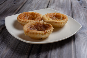 Three traditional bakewell puddings on a white plate side view