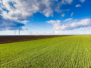 Beautiful bright Landscape with a Windfarm on a sunny day with a sky full of clouds and colorful foreground with green-yellowish grass