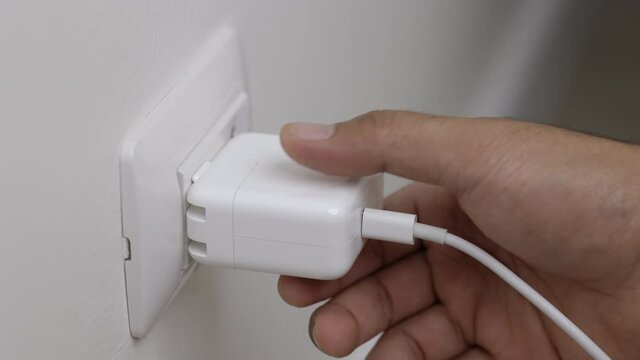 Close up male hand remove the Electric adapter smartphone or laptop plug. Electrical wires and power strips in the house