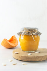 Pumpkin jam in a glass jar on a wooden board.