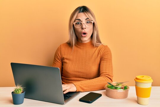 Young caucasian woman working at the office wearing glasses scared and amazed with open mouth for surprise, disbelief face