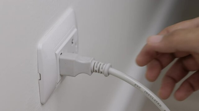Hand remove Electric plug on socket. Electrical equipment, electrical wires and power strips in the house. Earth Hour saving electrical energy.