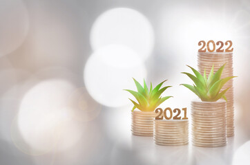 Fototapeta na wymiar New year 2021 to 2022 and growing money plant on stack of coins on abstract background. Future ahead return on investment for sustainability concept and business economic growth idea