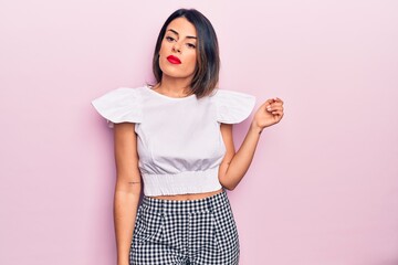 Young beautiful brunette woman wearing casual clothes standing over isolated pink background