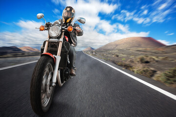 a biker on a motorcycle rides on an asphalt road in the mountains