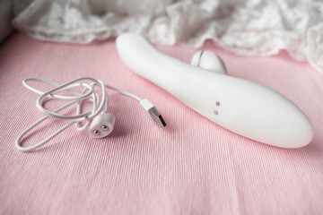 white silicone vibrator with vacuum mode on pink lace background with magnetic charging