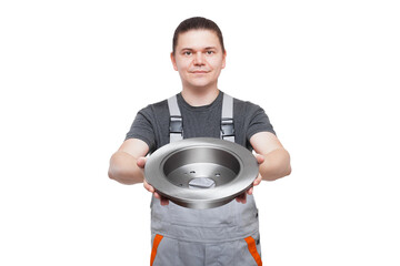 male mechanic in gray uniform holds brake disk in hands car spare parts of automobile brakes, shop sale of iron alloy product isolated on white background.