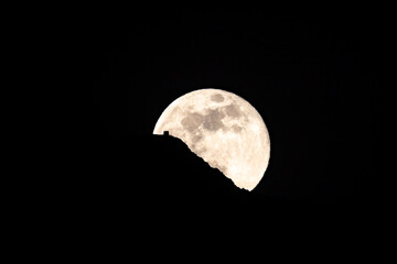 Luna llena saliendo por detrás de una montaña con la silueta de una casa  por detras © David