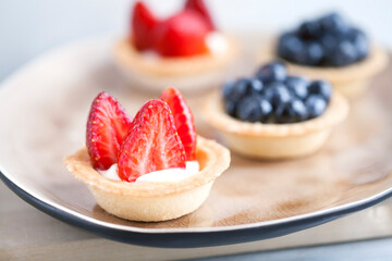 cake with cheese cream and fresh berries and wild berries on a beige plate on a wooden light background. Idea for culinary recipes and desserts. Perfect party concept.