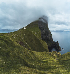 Kalsoy Island with Kallur lighthouse on on Faroe islands, Denmark, Europe. Clouds over high cliffs, turquoise Atlantic ocean and spectacular views.