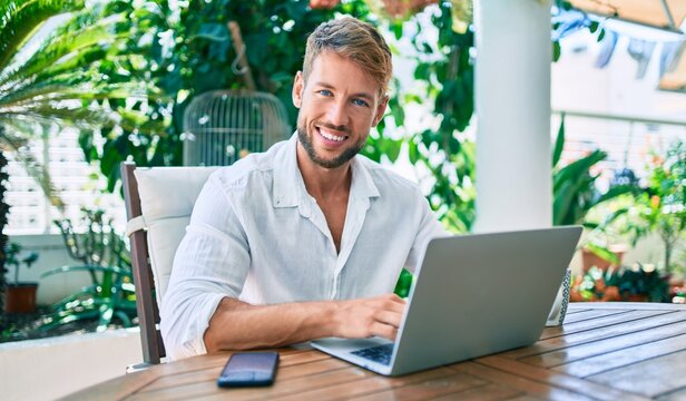 Handsome caucasian man sitting on the terrace working from home using computer laptop