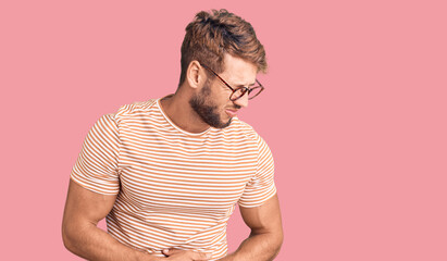 Young caucasian man wearing casual clothes and glasses with hand on stomach because indigestion, painful illness feeling unwell. ache concept.
