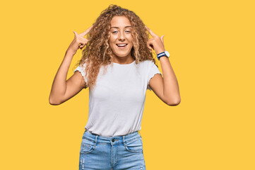 Beautiful caucasian teenager girl wearing casual white tshirt smiling pointing to head with both hands finger, great idea or thought, good memory