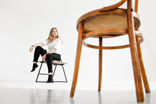 Low Angle View Of Woman Sitting On Seat Against White Background