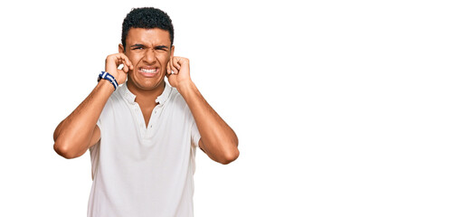 Young arab man wearing casual clothes covering ears with fingers with annoyed expression for the noise of loud music. deaf concept.