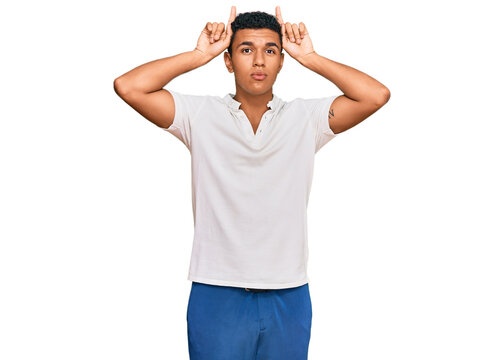Young arab man wearing casual clothes doing funny gesture with finger over head as bull horns